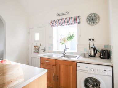 A kitchen with a wooden counter a sink a washing machine a kettle and a toaster at Windygates in Rhosneigr