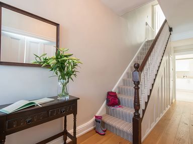 A hallway with stairs and flowers on a console table at West View in Rhosneigr
