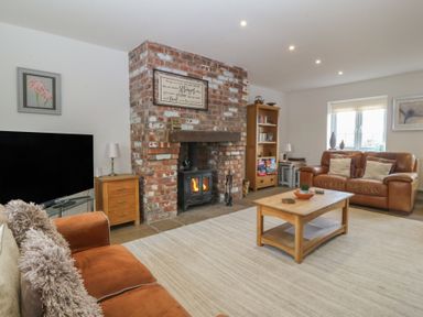 A living room with a sofa, fireplace, and TV at Llanallgo Church Rooms