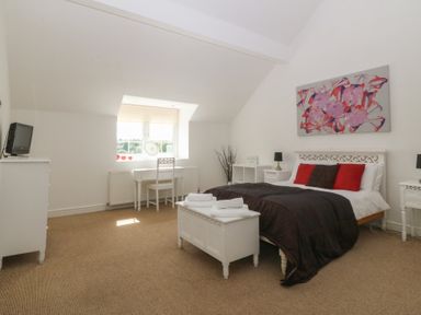 A bedroom with a bed, desk, and television at Llanallgo Church Rooms