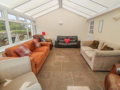 A conservatory with seating and a door at Llanallgo Church Rooms