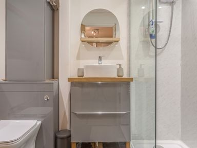 A bathroom with a toilet cabinet sink with mirror and a shower at Potters by the Sea in Sennen