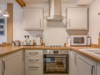 A kitchen with an oven stovetop microwave toaster and kettle at Potters by the Sea in Sennen