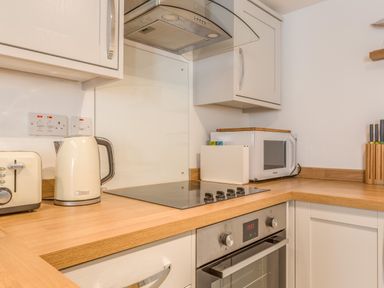 A kitchen countertop with a toaster kettle microwave stove oven and knife block at Potters by the Sea in Sennen