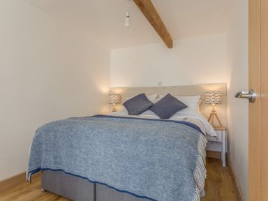 A bedroom with a double bed blue blankets and pillows bedside tables with lamps at Potters by the Sea in Sennen
