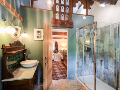 A bathroom with a sink on a wooden vanity and a glass shower door with rustic wooden tiles at Bonny Bits Cottage in Garrigill near Alston