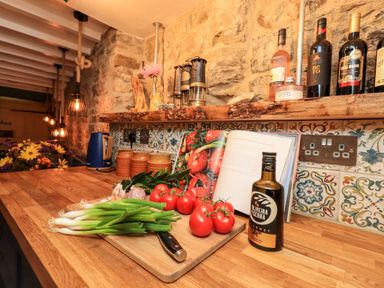 A kitchen counter with fresh vegetables a cookbook and bottles on a wooden counter at Bonny Bits Cottage in Garrigill near Alston