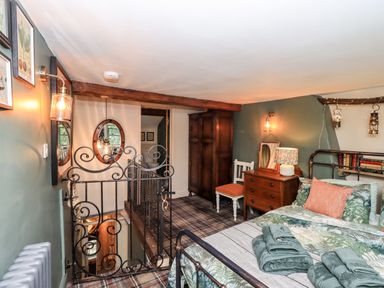 A bedroom with a metal bed frame a wooden dresser a chair and a wardrobe at Bonny Bits Cottage in Garrigill near Alston