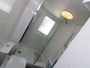 A bathroom with a shower area with glass door a toilet and a sink at Pebble Cottage in Portreath