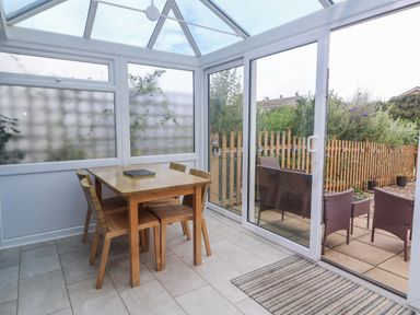 A conservatory with a table and chairs at Pebble Cottage in Portreath