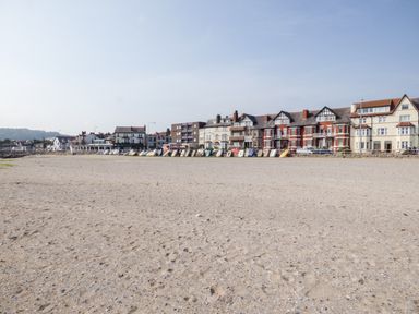 A sandy beach with boats lined up near a row of buildings at Sea Breeze in Rhos-on-Sea