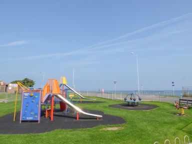 A playground area with slides and climbing equipment near the sea at Sea Breeze in Rhos-on-Sea