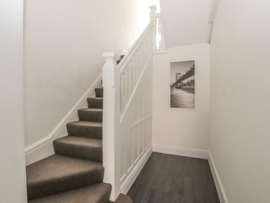 A carpeted staircase with white banister and a black and white photo on the wall at Sea Breeze in Rhos-on-Sea