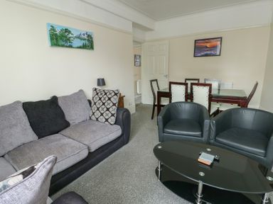 A living room with a sofa and dining area at Sea Breeze Rhos-on-Sea