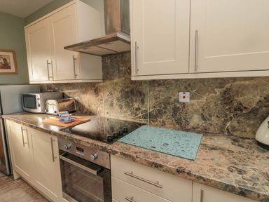 A kitchen countertop with microwave toaster cups stove and oven at Forge Cottage in Rothbury