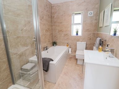 A bathroom with a bathtub shower toilet sink and towels at Forge Cottage in Rothbury