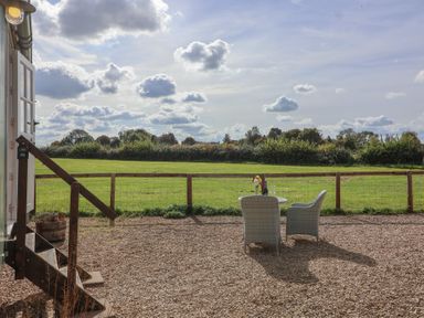 An outdoor seating area with a table and chairs at The Shepherds Hut in Chippenham