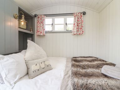A bedroom with a bed and pillows at The Shepherds Hut in Chippenham