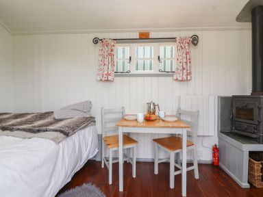 A sleeping area with a table and chairs at The Shepherds Hut in Chippenham