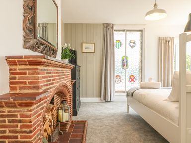 A bedroom with a brick fireplace bunk bed stained glass window and gray carpet at The Coach House in Teignmouth