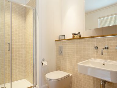 A bathroom with a glass shower enclosure toilet and sink with tiled walls at 3 Valley View Lanreath
