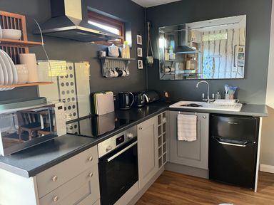 A kitchen with black countertops a microwave oven stove fridge and sink at Wellinghill Lodge in Cheltenham