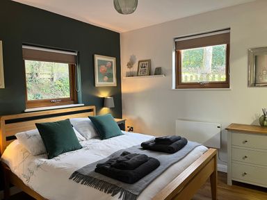 A bedroom with a double bed and folded towels on the blanket at Wellinghill Lodge in Cheltenham