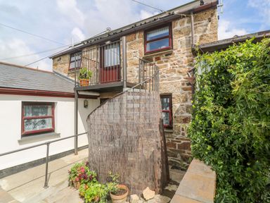 An exterior view of a stone building with a spiral staircase and potted plants at The Stables in Longrock