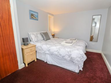 A bedroom with a double bed bedside tables lamps a wall mirror and a painting at The Stables in Longrock