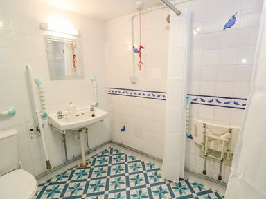 A bathroom with a toilet sink mirror and a shower with a curtain at The Stables in Longrock