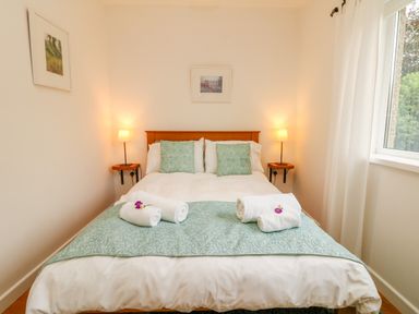 A bedroom with a double bed and rolled towels on a bed runner at Sunset in St Just