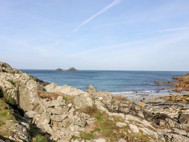 A rocky coastline with a view of the sea and small islands at Sunset in St Just