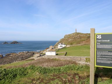 A coastal landscape with a signpost and buildings near the sea at Cape Cornwall