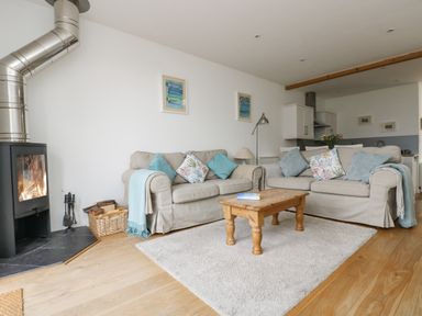 A living room with two sofas a wooden coffee table a rug and a fireplace at Sunset in St Just