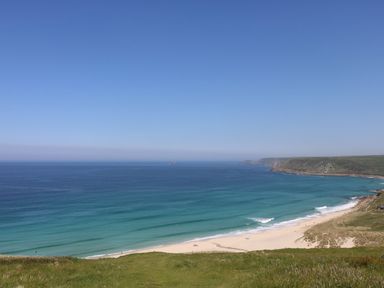 A beach with waves and hills at Sunset in St Just
