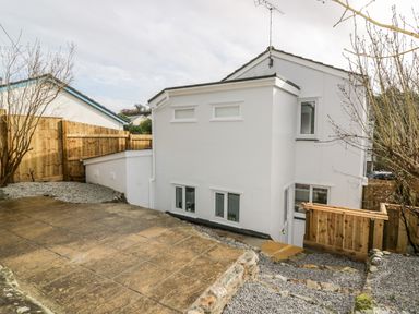 A backyard with a white house wooden fencing gravel and a stone path at Avalon in St Agnes
