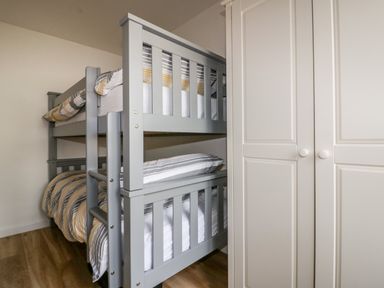A bedroom with a gray bunk bed and a white wardrobe at Avalon in St Agnes