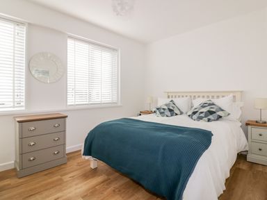 A bedroom with a double bed two side tables a chest of drawers and two windows with blinds at Avalon in St Agnes