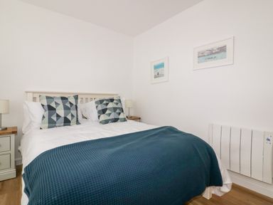 A bedroom with a double bed two bedside tables with lamps and framed pictures on the wall at Avalon in St Agnes