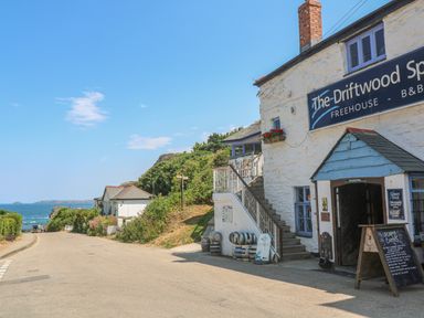 A street view with a white building with a sign The Driftwood Sparrow freehouse b b near a coastline at Avalon in St Agnes