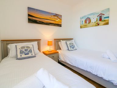 A bedroom with two single beds a nightstand and two paintings on the wall at Seashore in Woolacombe
