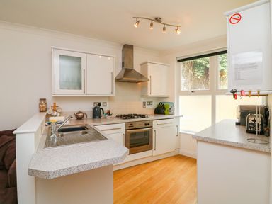 A kitchen with white cabinets wooden floor and stainless steel appliances at Seashore in Woolacombe