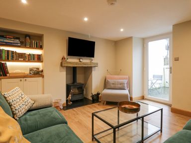 A living room with a green sofa a glass coffee table and a wood burning stove at St Mary's Cottage in Windermere