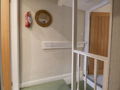 A hallway with a round mirror a fire extinguisher and a wooden door at St Marys Cottage in Windermere