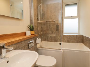 A bathroom with a white sink toilet and bathtub with shower at St Marys Cottage in Windermere