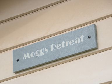 A sign with the text Moggs Retreat on an exterior wall at Moggs Retreat in Chapel St Leonards