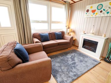A living room with a sofa and fireplace at Moggs Retreat in Chapel St Leonards