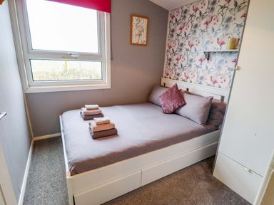 A bedroom with a bed and window at Moggs Retreat Chapel St Leonards