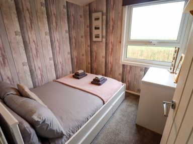 A bedroom with a bed and towels folded on top at Moggs Retreat in Chapel St Leonards