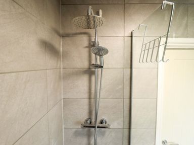 A shower area with showerhead and handheld shower at Moggs Retreat, Chapel St Leonards